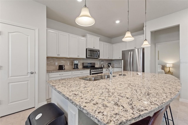 kitchen with decorative light fixtures, white cabinetry, backsplash, stainless steel appliances, and light tile floors