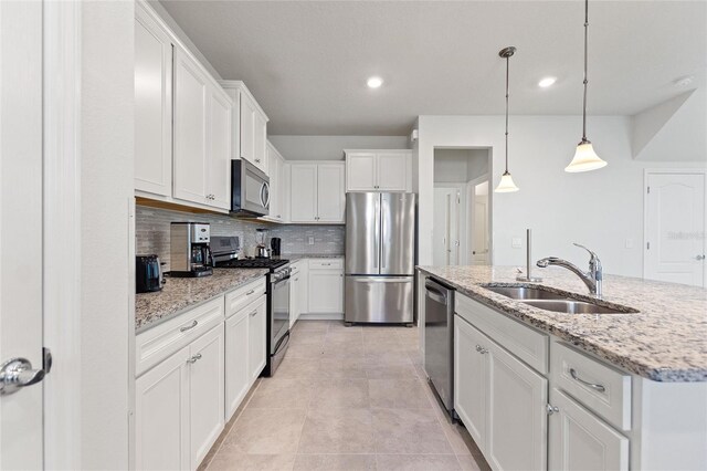 kitchen featuring hanging light fixtures, stainless steel appliances, white cabinets, light stone counters, and tasteful backsplash