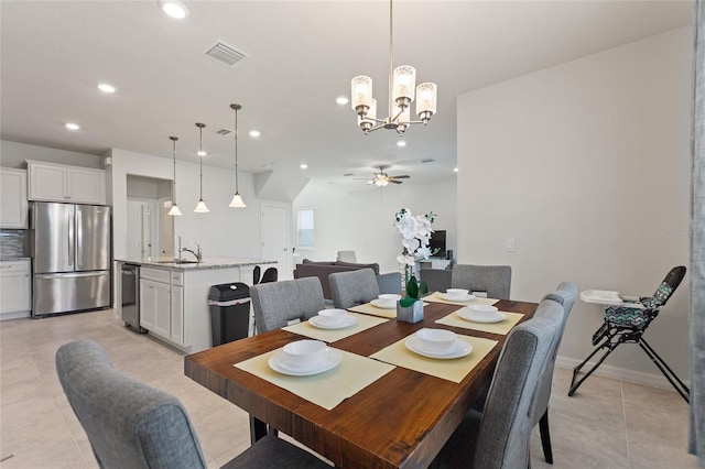 dining space with sink, ceiling fan with notable chandelier, and light tile flooring