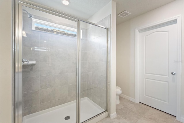 bathroom featuring toilet, tile floors, and a shower with shower door