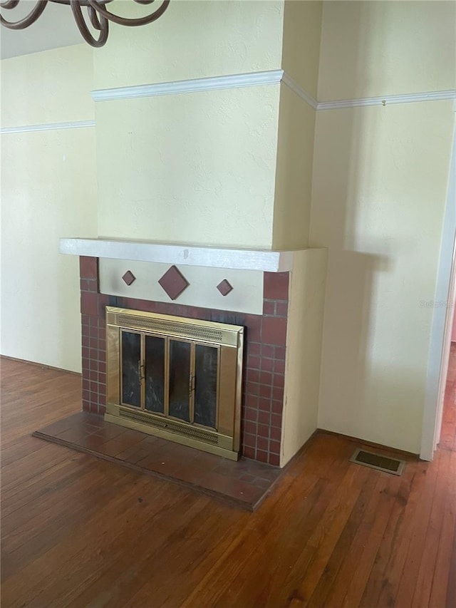 interior details featuring wood-type flooring and a tiled fireplace