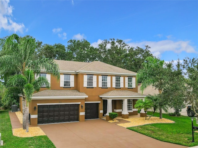 view of front of property featuring central air condition unit, a front lawn, and a garage