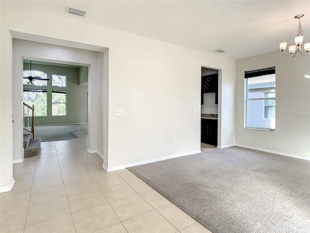 carpeted empty room featuring an inviting chandelier