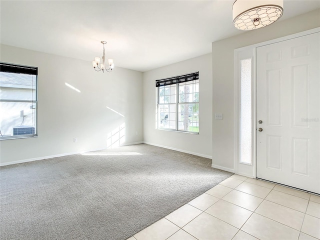 foyer entrance with light carpet and an inviting chandelier