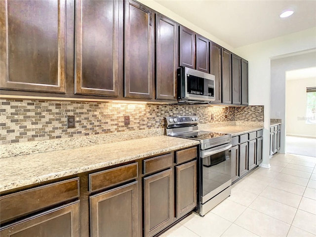 kitchen featuring decorative backsplash, dark brown cabinets, stainless steel appliances, and light tile patterned floors