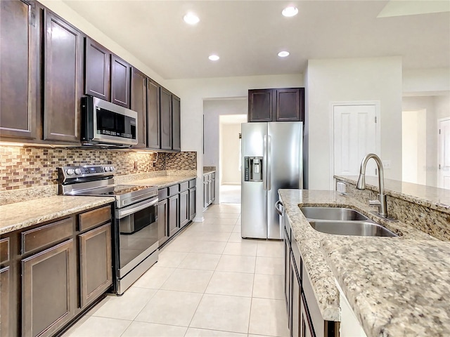 kitchen with sink, light stone countertops, stainless steel appliances, and dark brown cabinetry