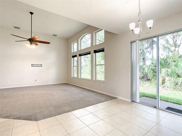 carpeted spare room with ceiling fan with notable chandelier and high vaulted ceiling