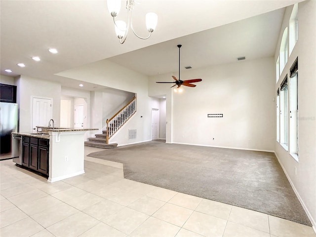 unfurnished living room with ceiling fan with notable chandelier, light colored carpet, and sink