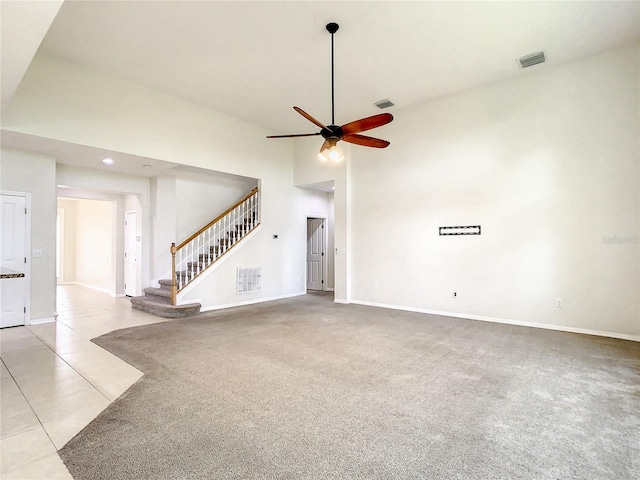 unfurnished living room with ceiling fan, light tile patterned floors, and a high ceiling