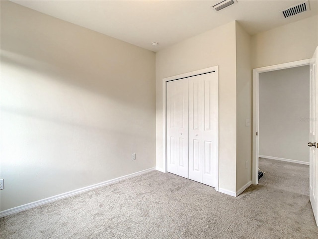 unfurnished bedroom featuring light carpet and a closet