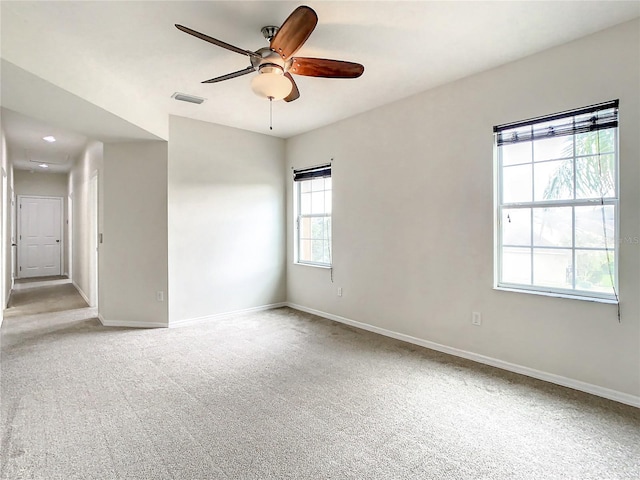 unfurnished room with light colored carpet, plenty of natural light, and ceiling fan