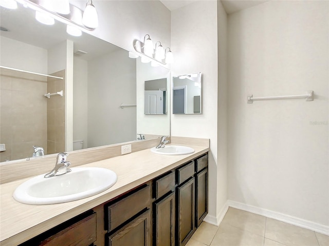 bathroom with tile patterned floors, vanity, a tile shower, and toilet