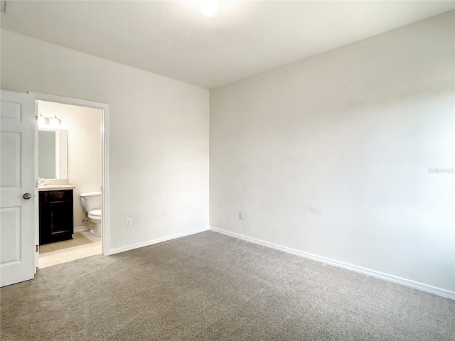 unfurnished bedroom with connected bathroom and light colored carpet