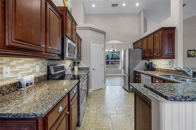 10120 Lakeshore Dr, Clermont, FL 34711 - kitchen with stainless steel appliances, a high ceiling, tasteful backsplash, stone tile floors, and dark stone counters