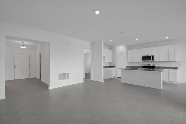 kitchen featuring white cabinets, electric range oven, light tile patterned flooring, and a center island