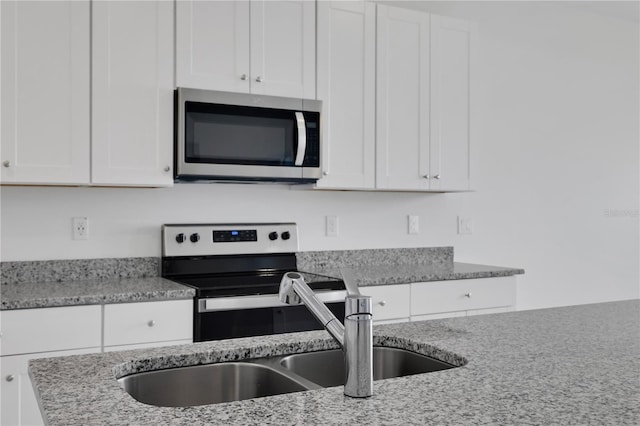 kitchen with white cabinets, electric range oven, sink, and light stone counters