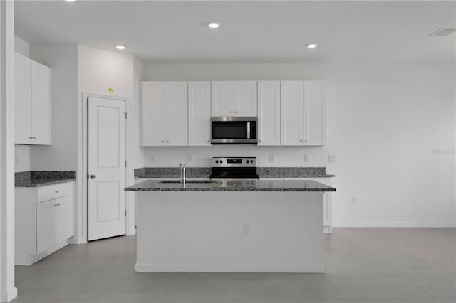 kitchen with stainless steel appliances, white cabinets, and a center island with sink