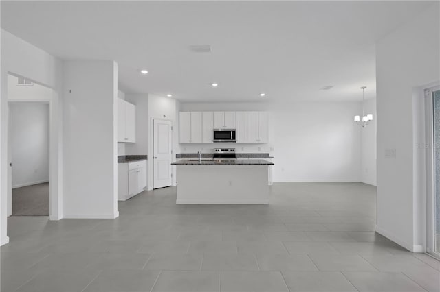 kitchen featuring stainless steel appliances, a notable chandelier, sink, a kitchen island with sink, and white cabinetry