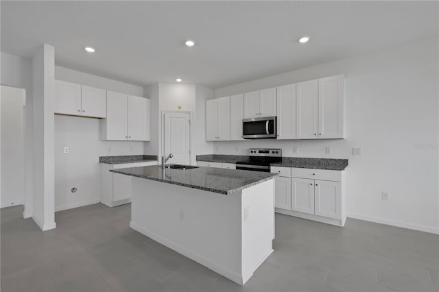 kitchen with a center island with sink, white cabinetry, appliances with stainless steel finishes, sink, and dark stone countertops