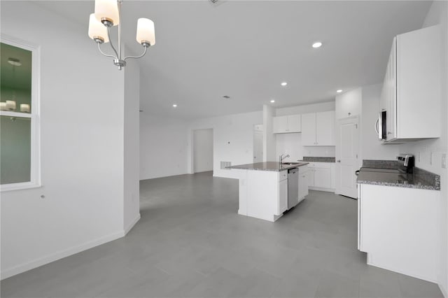 kitchen with white cabinetry, sink, appliances with stainless steel finishes, an island with sink, and hanging light fixtures