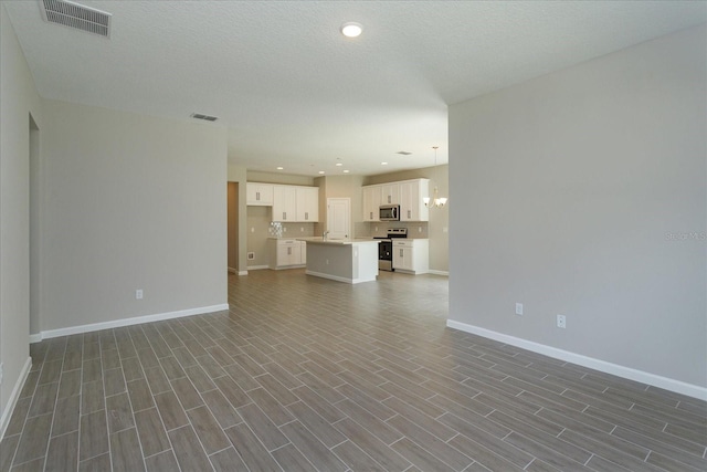 unfurnished living room featuring a textured ceiling and dark hardwood / wood-style flooring