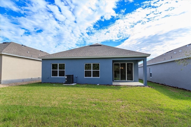 rear view of house with central AC unit and a yard