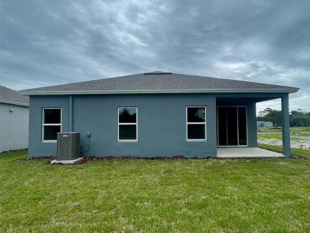 rear view of house with central AC unit and a lawn