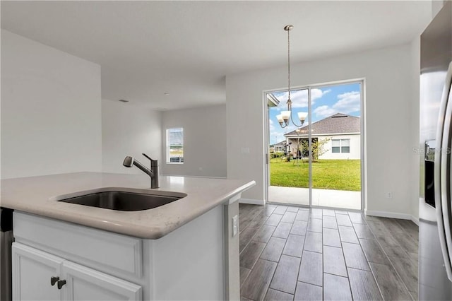 kitchen with white cabinets, a chandelier, a healthy amount of sunlight, and sink