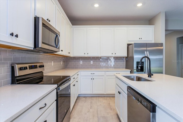 kitchen featuring white cabinets, light hardwood / wood-style flooring, tasteful backsplash, and stainless steel appliances