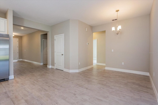 empty room with an inviting chandelier and light wood-type flooring