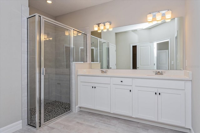 bathroom with hardwood / wood-style floors, double vanity, and walk in shower