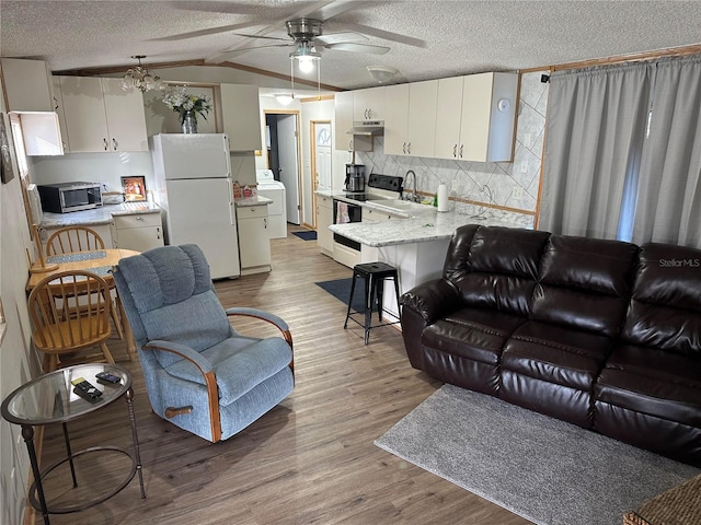 living room featuring washer / clothes dryer, light hardwood / wood-style floors, a textured ceiling, and ceiling fan