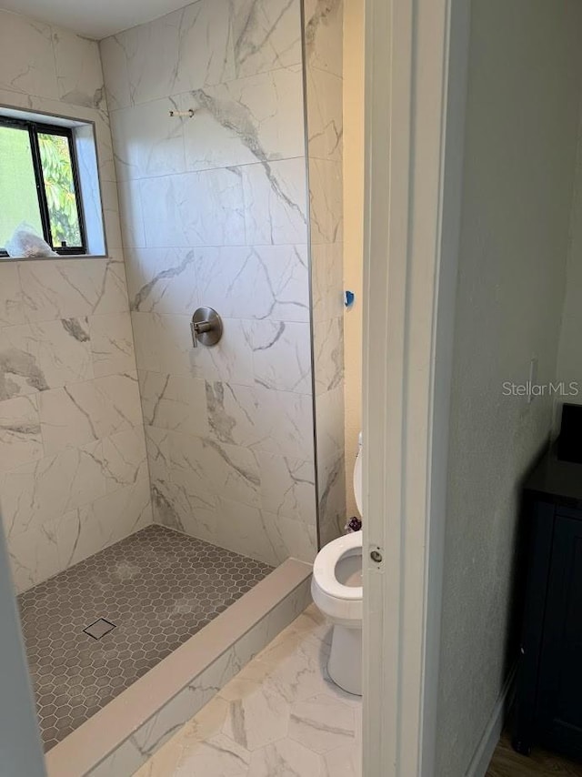 bathroom featuring toilet, a tile shower, and tile floors