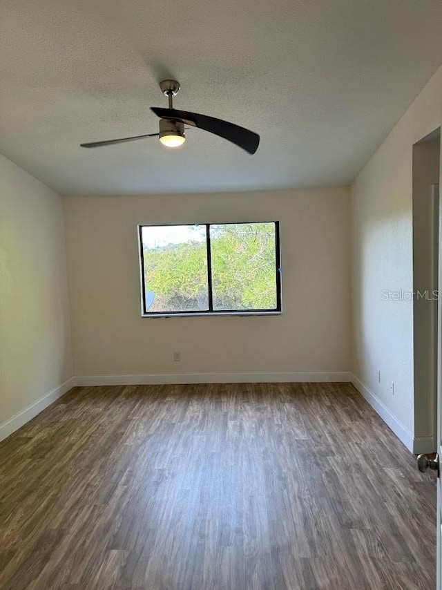 unfurnished room with ceiling fan, a textured ceiling, and dark wood-type flooring