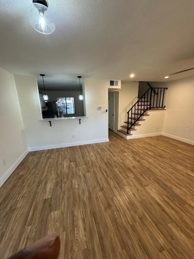 unfurnished living room with a textured ceiling and hardwood / wood-style flooring