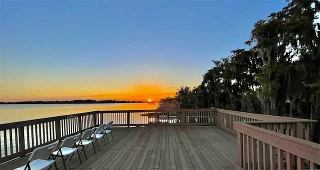 deck at dusk featuring a water view