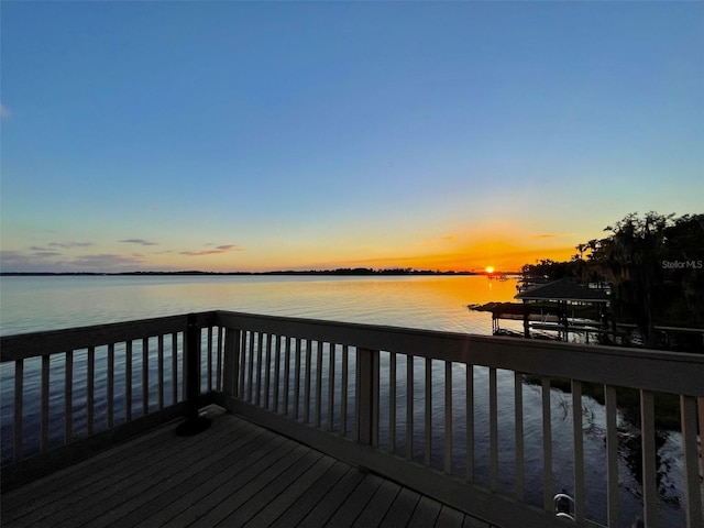 deck at dusk featuring a water view