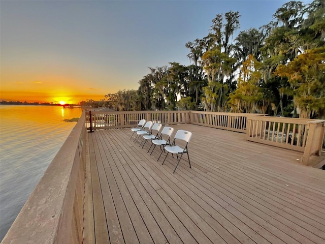 deck at dusk featuring a water view