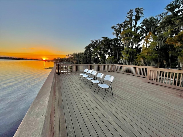 deck at dusk featuring a water view