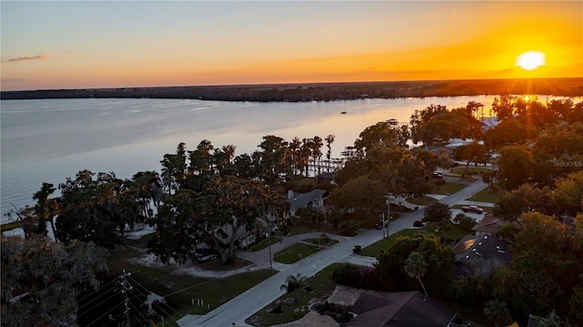 aerial view at dusk featuring a water view