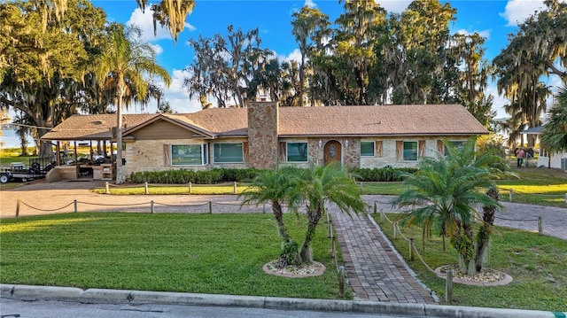 ranch-style home featuring a carport and a front lawn