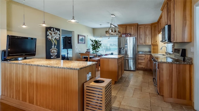 kitchen featuring sink, stainless steel appliances, a center island, decorative light fixtures, and dark stone counters