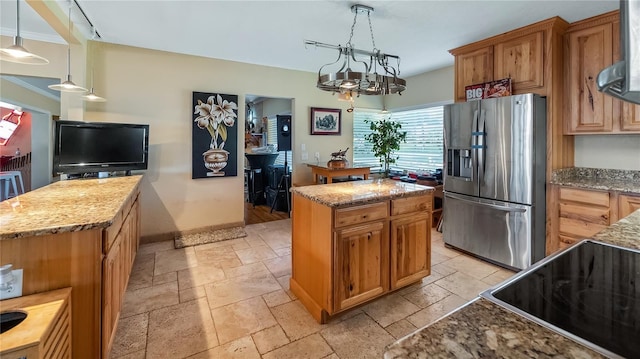 kitchen with hanging light fixtures, a center island, stainless steel fridge with ice dispenser, light stone countertops, and wall chimney range hood