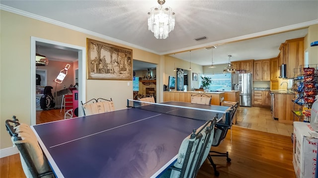 recreation room with a notable chandelier, crown molding, and wood-type flooring