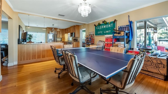 playroom with a notable chandelier, ornamental molding, and light wood-type flooring