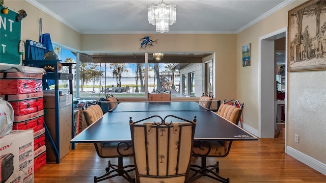 dining room with wood-type flooring, ornamental molding, and a chandelier