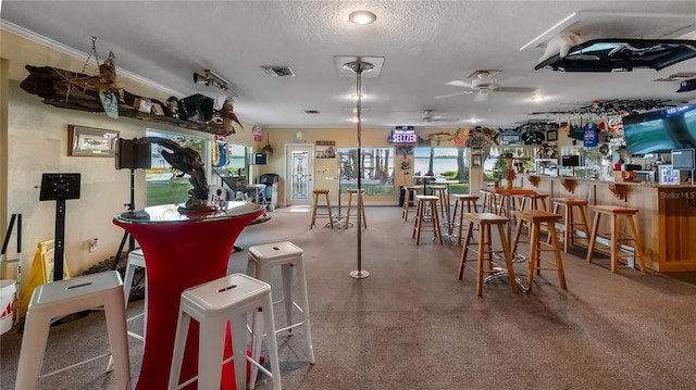 dining area with ceiling fan, bar, and a textured ceiling