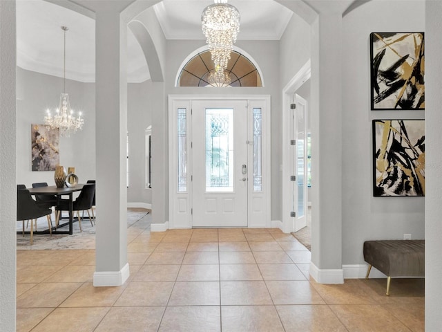 foyer entrance with light tile patterned floors, ornamental molding, baseboards, and an inviting chandelier