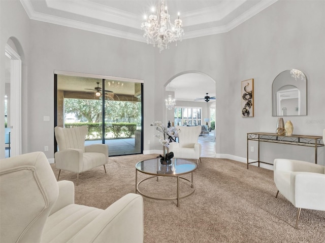 carpeted living room featuring ceiling fan with notable chandelier, a raised ceiling, and ornamental molding