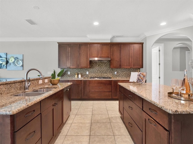 kitchen featuring light stone countertops, crown molding, sink, light tile patterned floors, and an island with sink